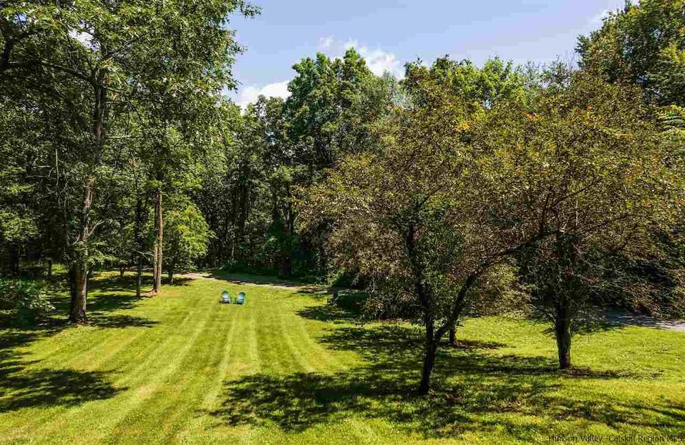 long expansive lawn with two blue chair and trees on the edges