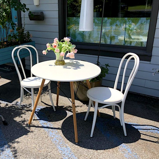 round white table with chairs out front and a vase with pink flowers