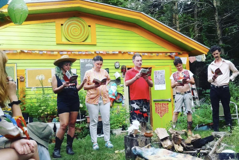peaople standing in the garden reading from books to the crowd