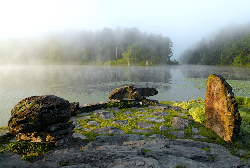 misty landscape of pond with rocks