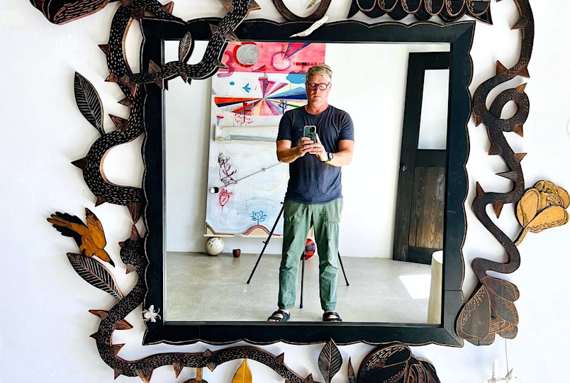 Jonah reflecting through his handmade large mirror with crafted adornments all around the frame