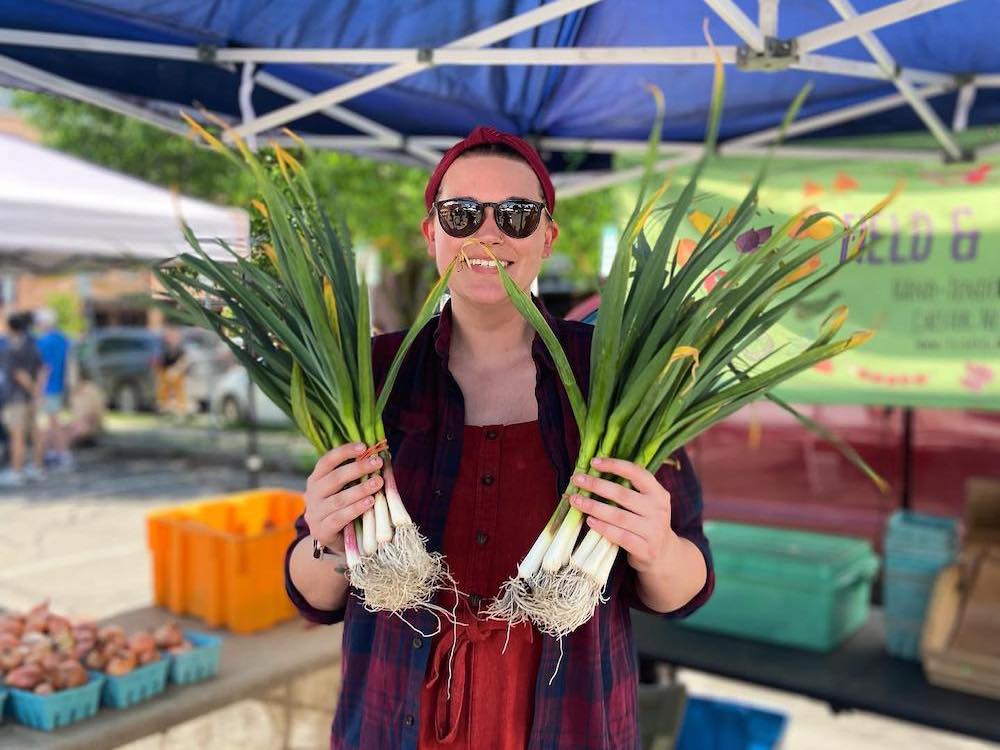 woman holding green onions at Beacon Farmers Market