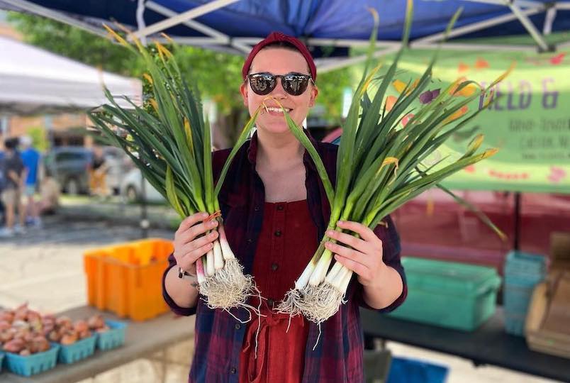woman with veggies in her hand at a market