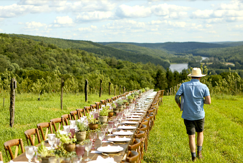 man walking past a long table set up for dinner