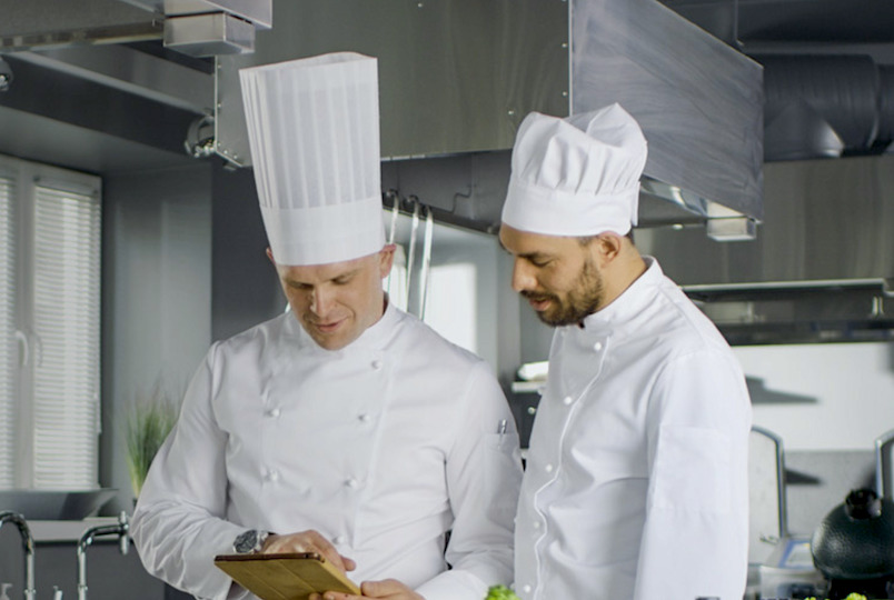 two chefs looking over a menu in the kitchen