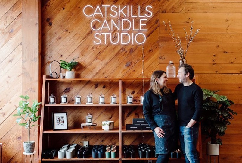 Two people inside with candles on the wooden wall from Catskills Candle Studio in Tannersville NY