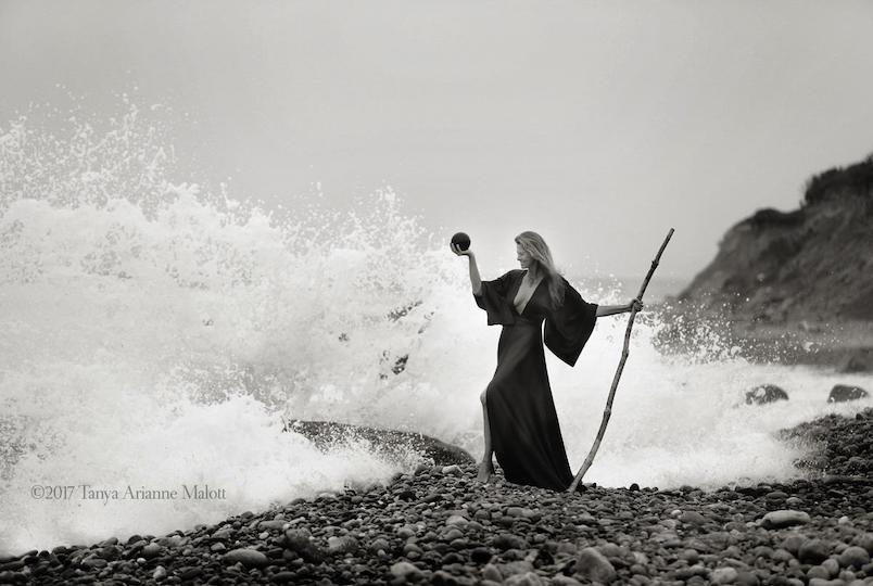 B&W photo of a woman on the beach against the backdrop of splashing waves taken by Tanya Arianne Malott Photography in Hudson NY