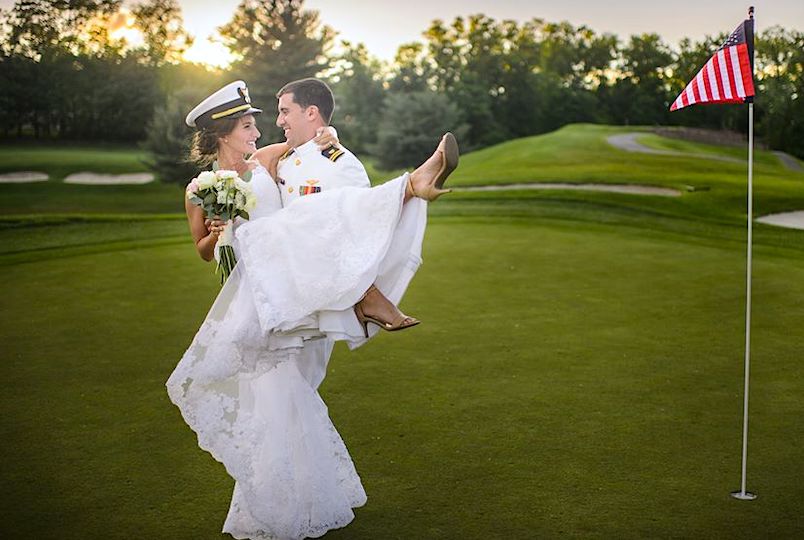 Groom with Bride in his arms next to a golf hole on the course at the West Hills Country Club Gold course and country club in Middletown NY