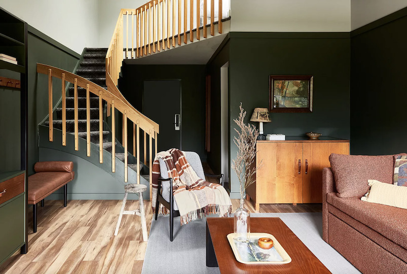 Living room with stairs to the loft and furniture that looks cozy at Bluebird Hunter Lodge in Hunter NY