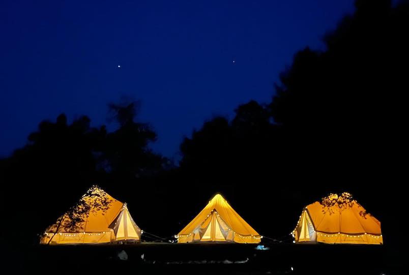 three glowing glamping tents with the night sky and stars by GlampStar in Woodstock NY