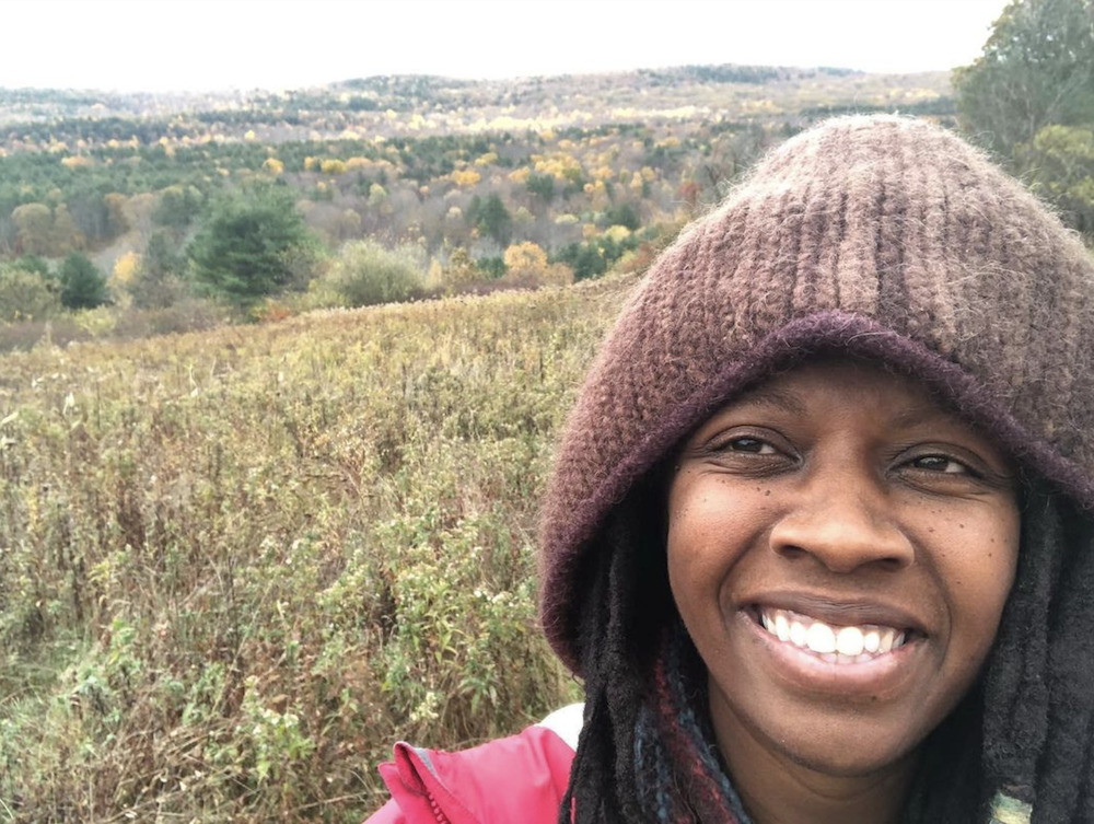 Farmer smiles with field behind her at Harmony Homestead & Wholeness Center in Copake NY