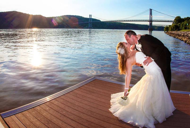 Bride and groom on a dock overlooking the bridge and Hudson River at The Grandview in Poughkeepsie NY