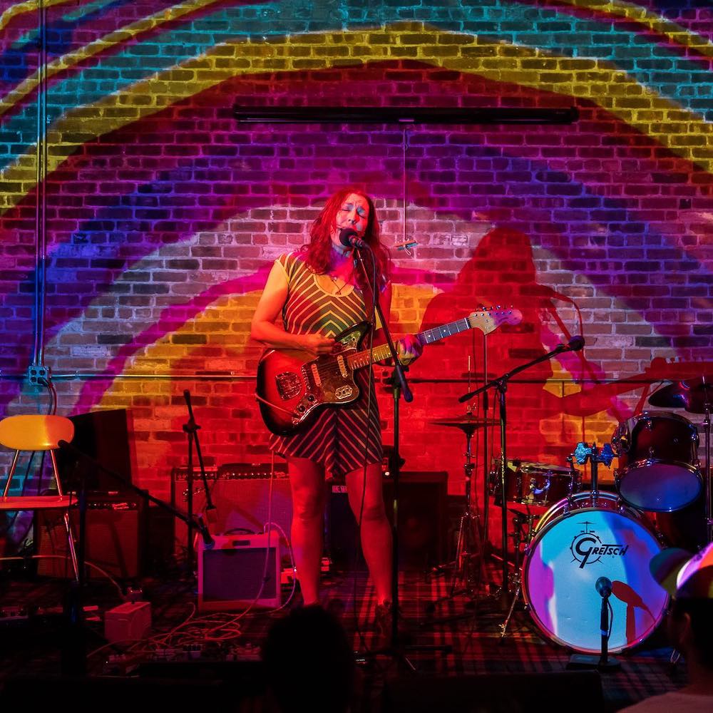 Shana Falana on stage performing at Basilica Hudson with rainbow stuff around