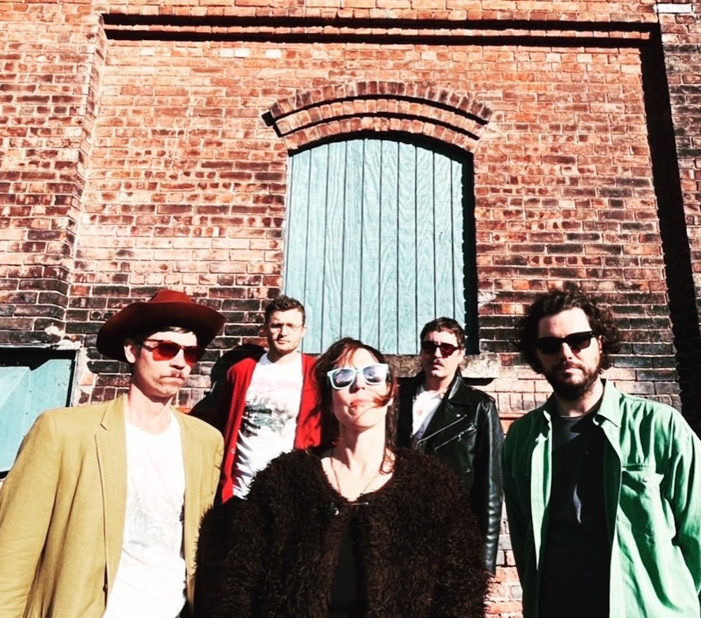 Shana Falana and Crawlbabies posing in front of a brick building